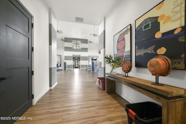 hallway with light hardwood / wood-style flooring and a high ceiling