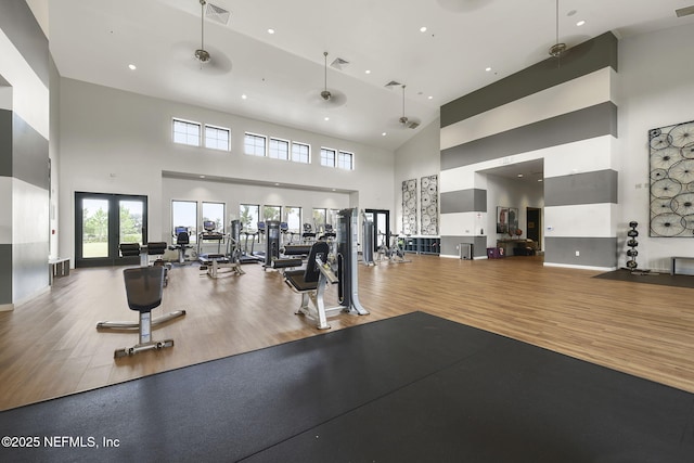 exercise room with a high ceiling, hardwood / wood-style floors, and french doors