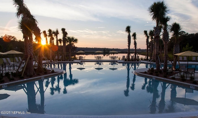 pool at dusk featuring a water view