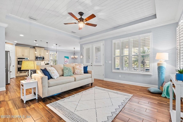 living room with plenty of natural light, a raised ceiling, and light wood-type flooring