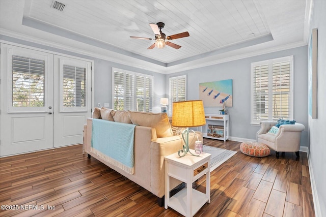 living room featuring wood ceiling, crown molding, dark wood-type flooring, ceiling fan, and a raised ceiling