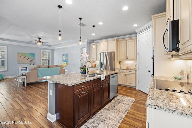 kitchen with dark brown cabinetry, sink, hanging light fixtures, stainless steel appliances, and cream cabinetry