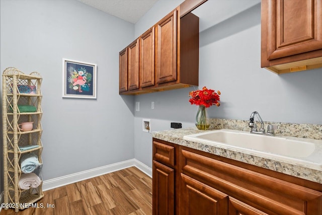 clothes washing area featuring sink, hookup for a washing machine, cabinets, hookup for an electric dryer, and light wood-type flooring