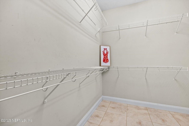 walk in closet with light tile patterned floors