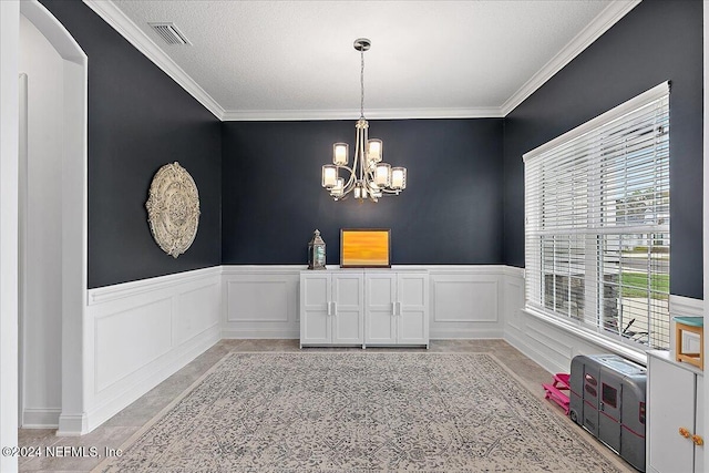 dining area with ornamental molding, a textured ceiling, and a notable chandelier