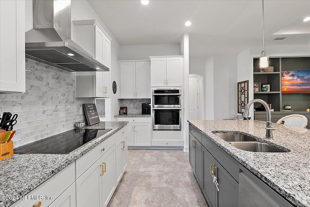 kitchen featuring wall chimney exhaust hood, dishwasher, sink, and white cabinets