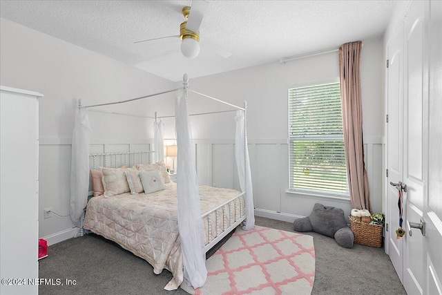 bedroom with ceiling fan, carpet floors, and a textured ceiling