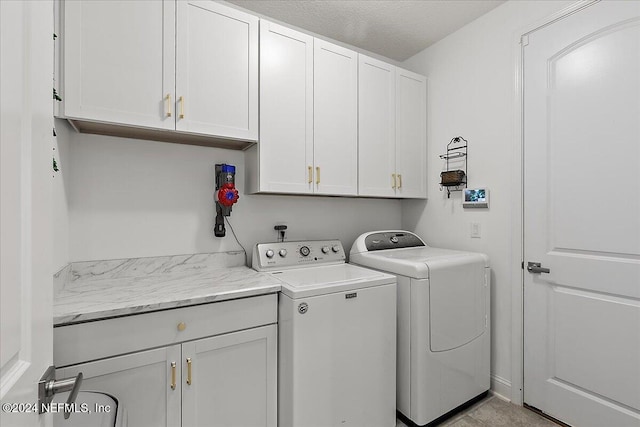 laundry area with cabinets, washer and clothes dryer, and a textured ceiling