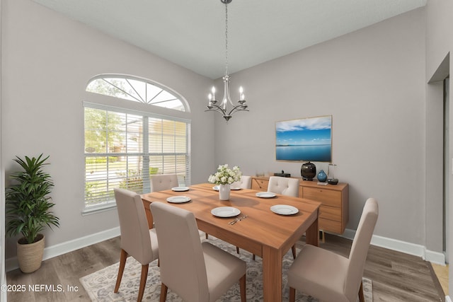 dining room featuring lofted ceiling, hardwood / wood-style floors, and a chandelier