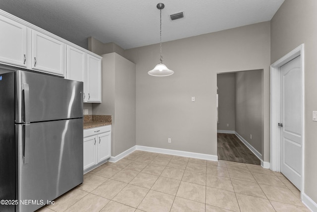 kitchen with stainless steel fridge, a textured ceiling, white cabinets, decorative light fixtures, and light tile patterned flooring