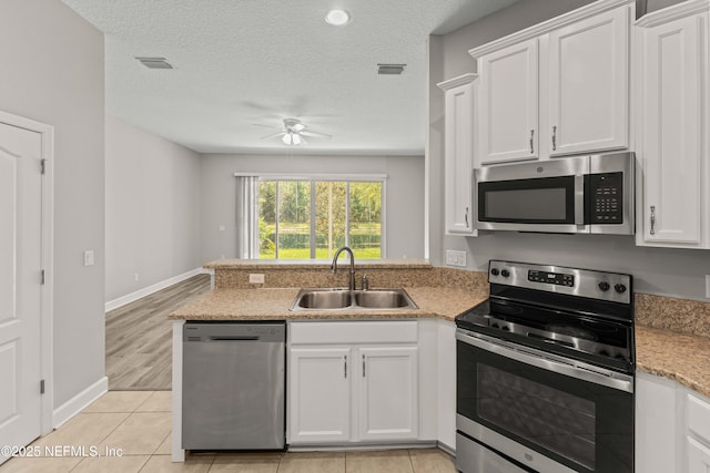 kitchen featuring appliances with stainless steel finishes, sink, a textured ceiling, and white cabinets