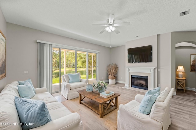 living room with ceiling fan, light hardwood / wood-style floors, and a textured ceiling