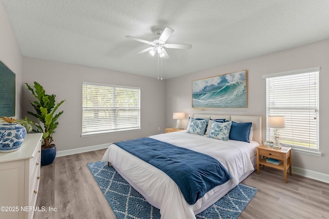 bedroom featuring ceiling fan, a textured ceiling, and light hardwood / wood-style floors