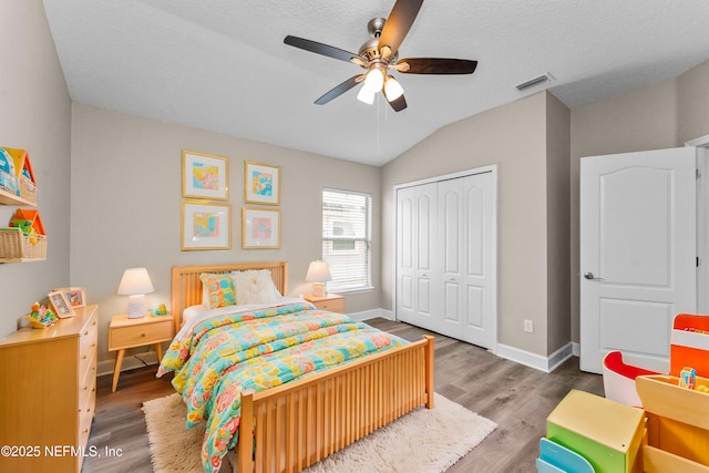 bedroom with vaulted ceiling, wood-type flooring, ceiling fan, a textured ceiling, and a closet