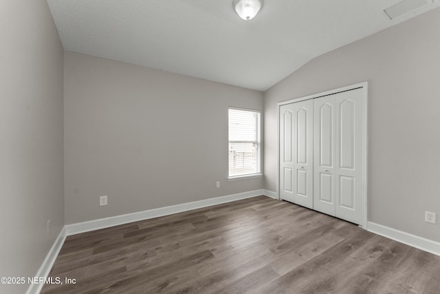 unfurnished bedroom featuring lofted ceiling, hardwood / wood-style flooring, and a closet