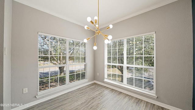 unfurnished dining area featuring an inviting chandelier, crown molding, and wood-type flooring