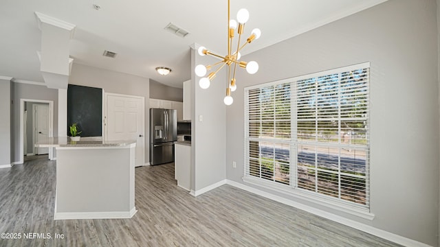 kitchen with crown molding, a chandelier, light hardwood / wood-style flooring, stainless steel fridge, and white cabinets