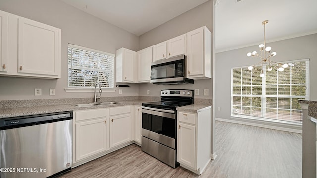 kitchen with appliances with stainless steel finishes, pendant lighting, white cabinetry, sink, and light hardwood / wood-style floors