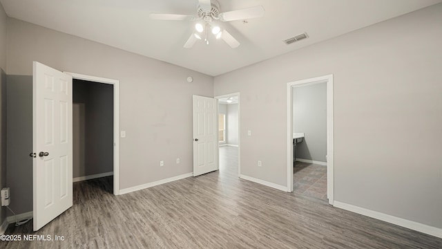 unfurnished bedroom with a walk in closet, hardwood / wood-style floors, and ceiling fan