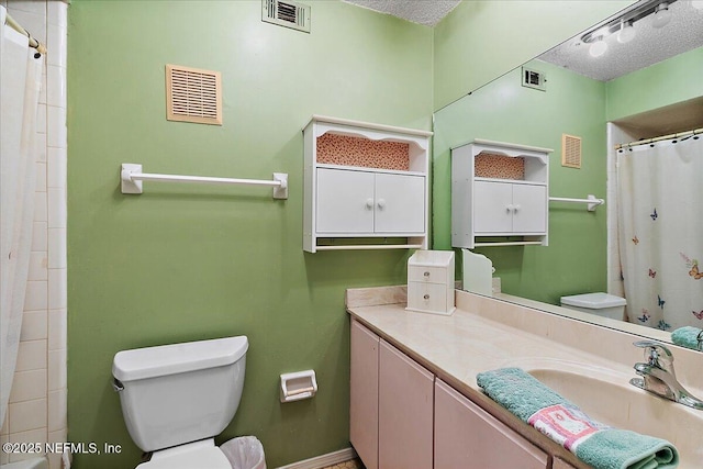 bathroom with vanity, toilet, and a textured ceiling