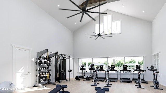 gym with ceiling fan, light hardwood / wood-style flooring, and a high ceiling