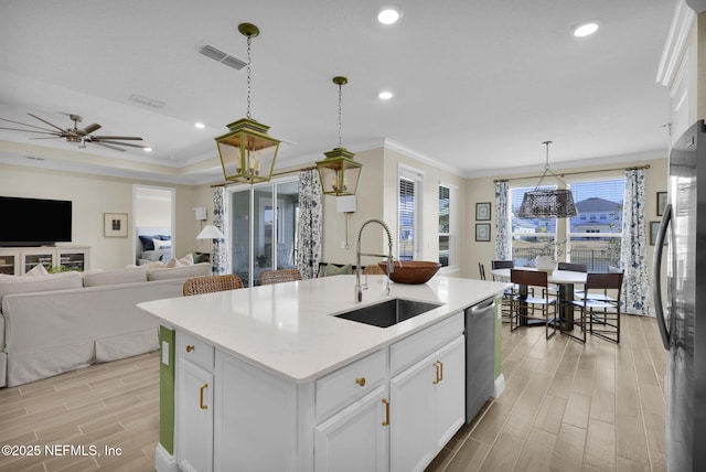 kitchen featuring sink, white cabinetry, decorative light fixtures, stainless steel appliances, and a kitchen island with sink