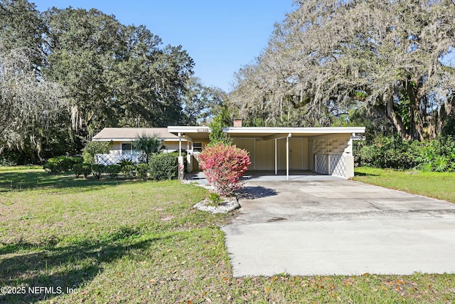 view of front of home featuring a carport, a front yard, concrete driveway, and a chimney