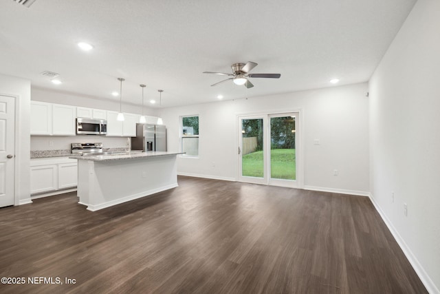 kitchen featuring white cabinetry, appliances with stainless steel finishes, dark hardwood / wood-style floors, an island with sink, and pendant lighting