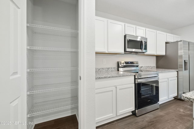 kitchen with appliances with stainless steel finishes, dark hardwood / wood-style floors, and white cabinets