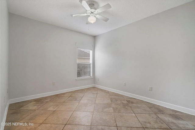 empty room featuring light tile patterned flooring, ceiling fan, and baseboards