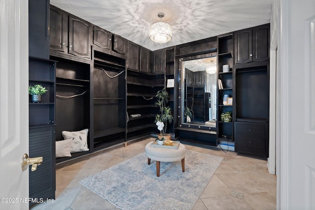 spacious closet featuring light tile patterned floors and an inviting chandelier