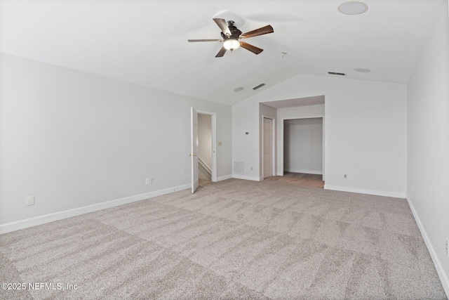 carpeted spare room featuring a ceiling fan, lofted ceiling, visible vents, and baseboards