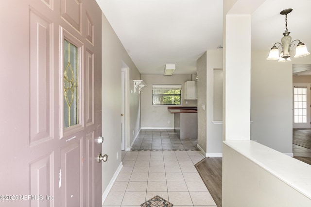 tiled entryway featuring an inviting chandelier and a healthy amount of sunlight