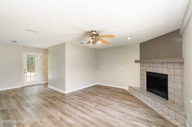 unfurnished living room featuring ceiling fan, light wood-type flooring, a textured ceiling, and a fireplace