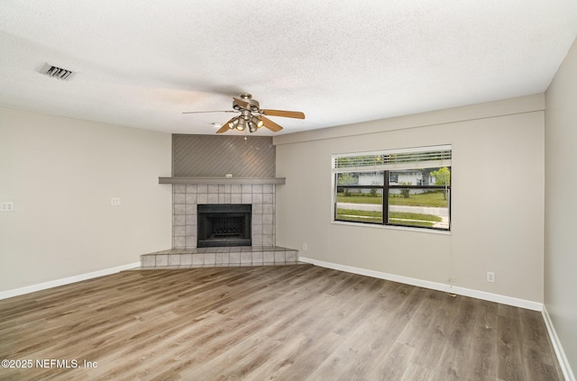 unfurnished living room featuring hardwood / wood-style flooring, ceiling fan, a textured ceiling, and a fireplace