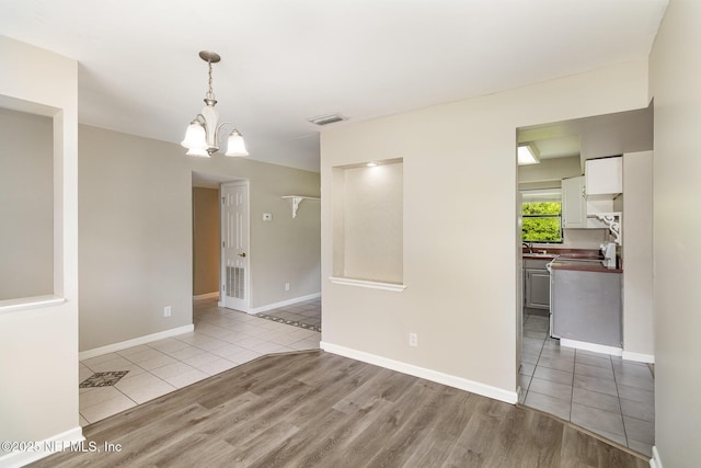 spare room featuring an inviting chandelier, light tile patterned floors, and sink