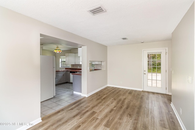 unfurnished room with light hardwood / wood-style floors and a textured ceiling