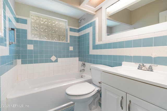 full bathroom featuring tiled shower / bath combo, vanity, tile walls, and toilet