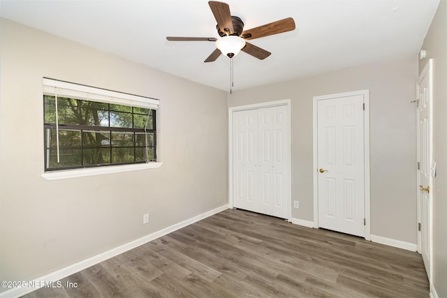 unfurnished bedroom featuring dark hardwood / wood-style flooring, a closet, and ceiling fan