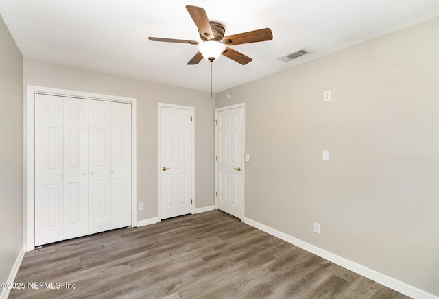 unfurnished bedroom with wood-type flooring, a closet, and ceiling fan