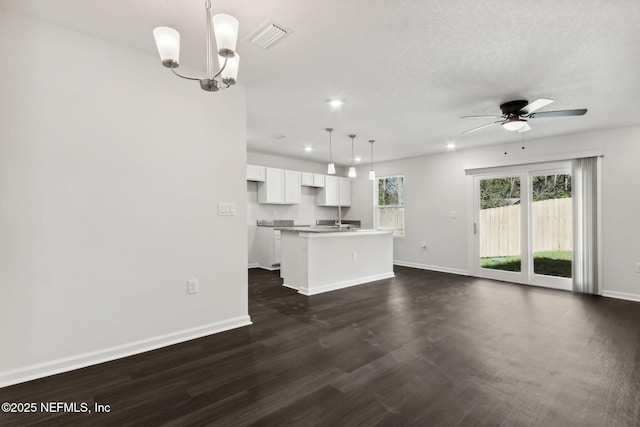 unfurnished living room with dark hardwood / wood-style floors, ceiling fan with notable chandelier, and a textured ceiling