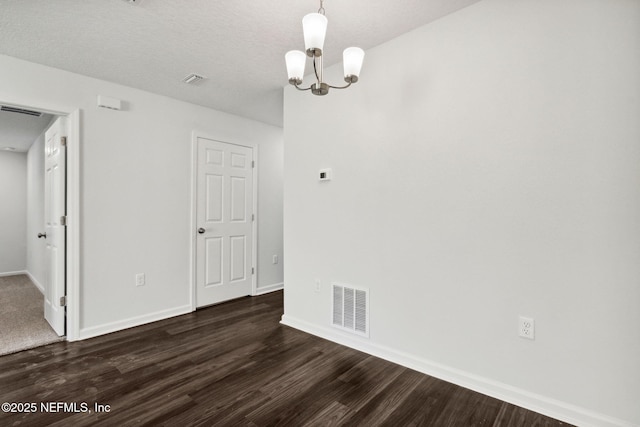 spare room with dark wood-type flooring, a notable chandelier, and a textured ceiling