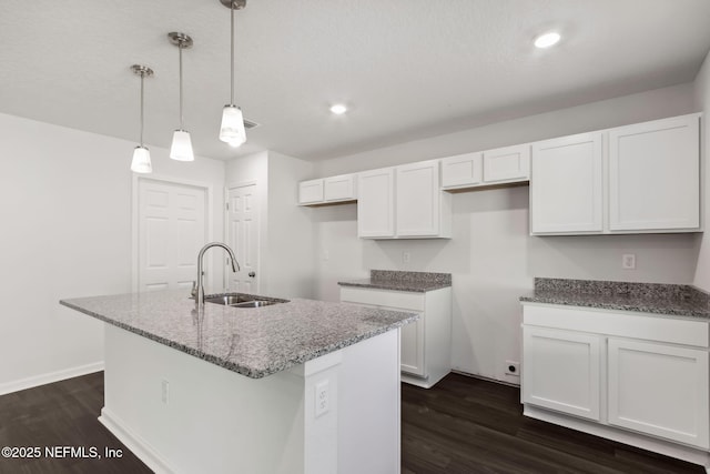 kitchen with dark stone countertops, sink, decorative light fixtures, and white cabinetry