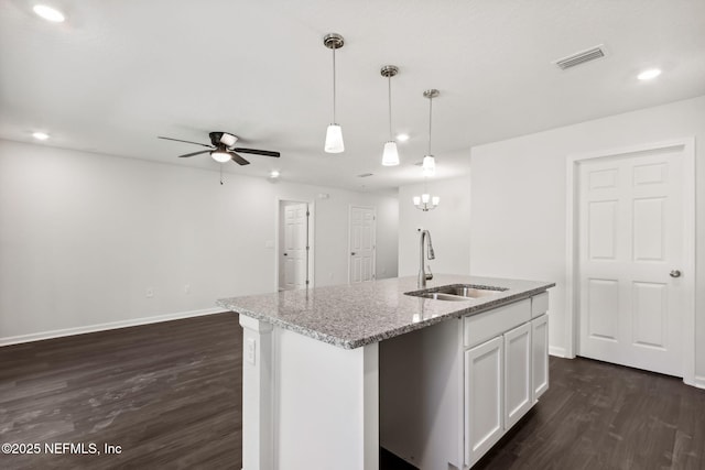 kitchen featuring sink, white cabinetry, hanging light fixtures, an island with sink, and light stone countertops