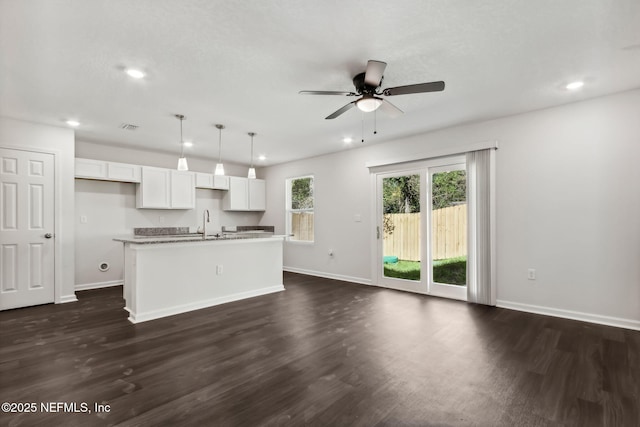 kitchen with decorative light fixtures, white cabinetry, dark hardwood / wood-style flooring, a kitchen island with sink, and ceiling fan