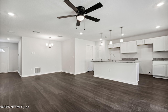 kitchen featuring sink, white cabinetry, hanging light fixtures, dark hardwood / wood-style floors, and an island with sink