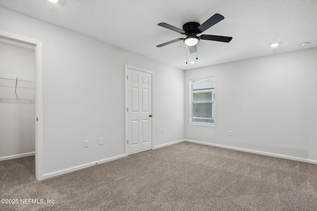 unfurnished bedroom featuring a walk in closet, carpet, ceiling fan, and a closet