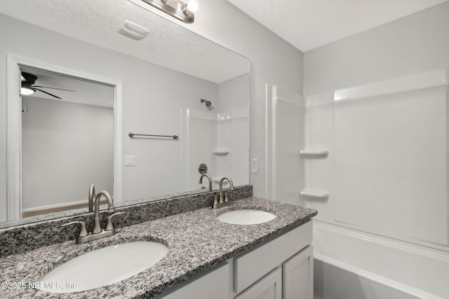 bathroom with ceiling fan, shower / tub combination, vanity, and a textured ceiling