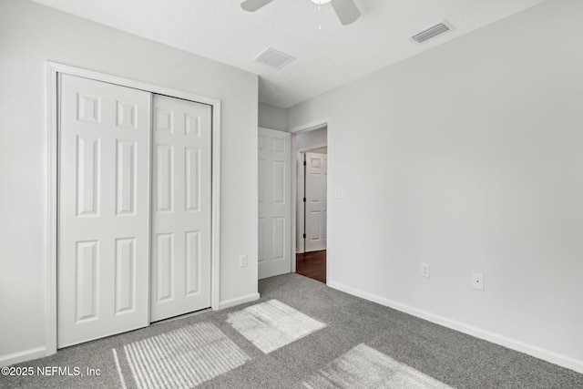 unfurnished bedroom with carpet flooring, a textured ceiling, ceiling fan, and a closet