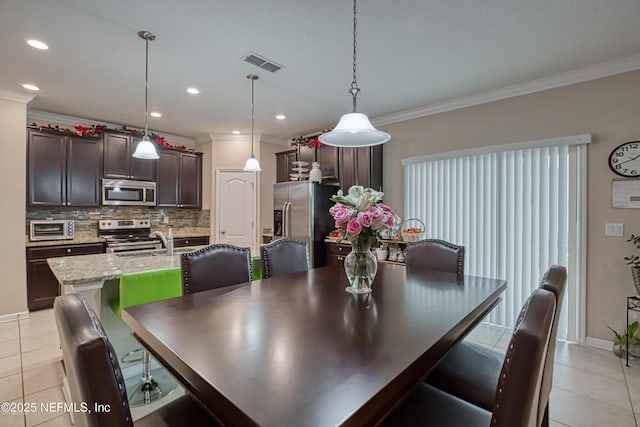 dining space featuring crown molding, sink, and light tile patterned floors